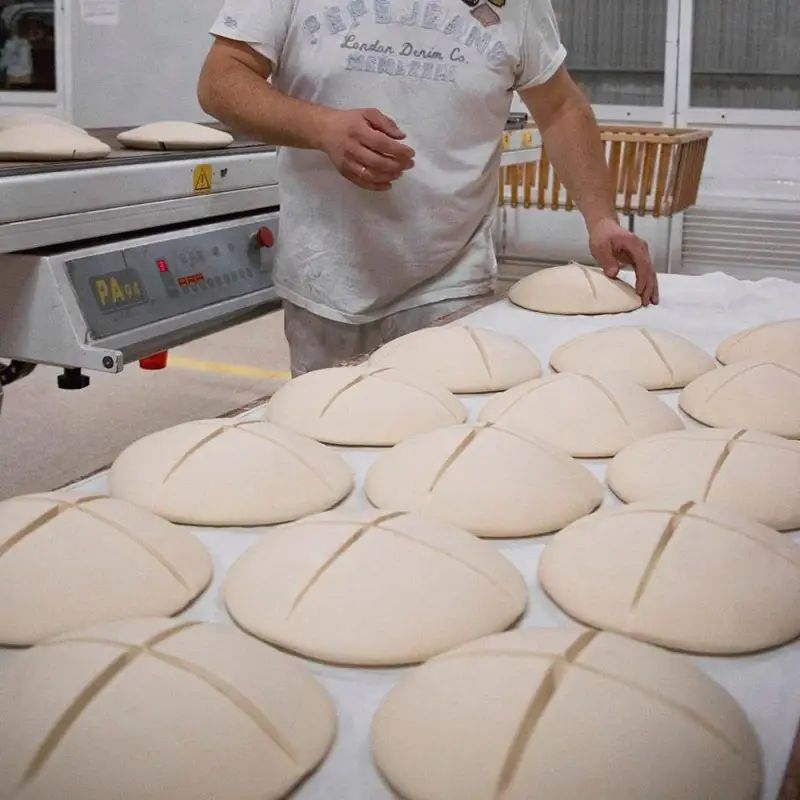 Panadero marcando la cruz en las piezas de masa antes de hornear