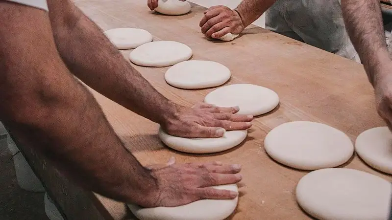 Panaderos dando forma a la masa del pan de cruz en el obrador